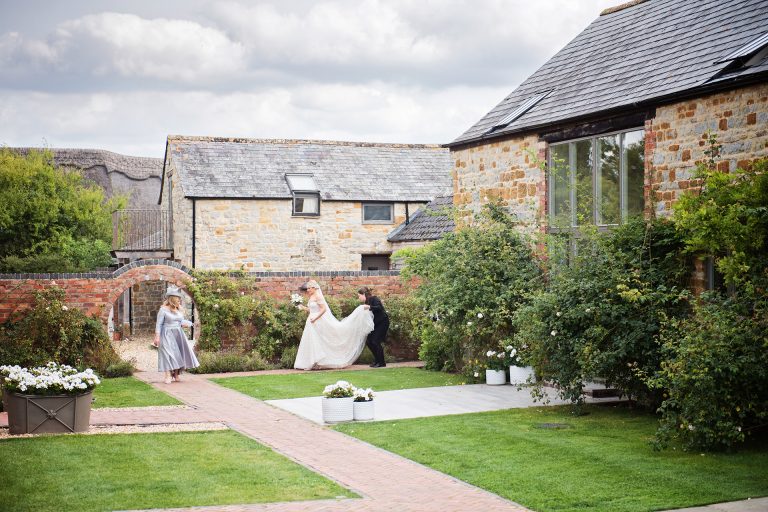 Bride walk down a garden path on their way to the wedding at Blackwell Grange.