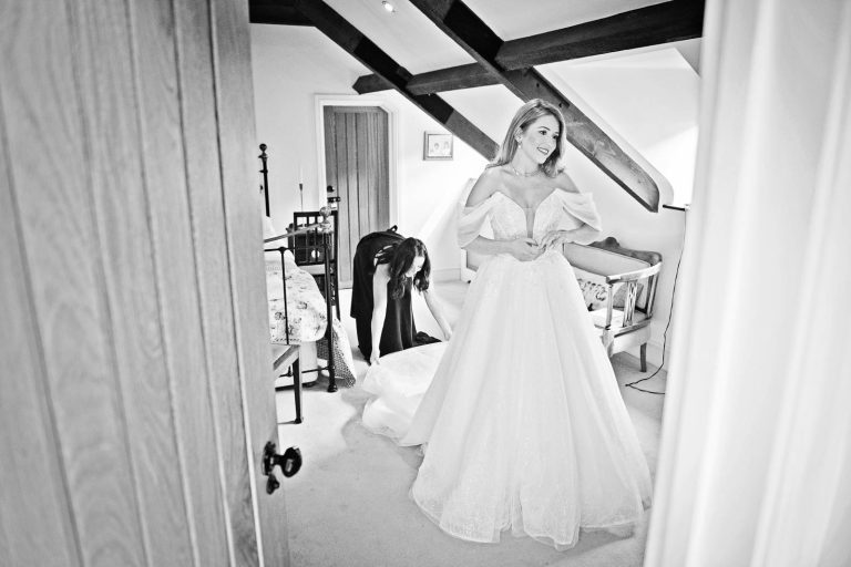 Black & white documentary photo of bride putting on her wedding dress by Cardiff wedding photographer, Blooming Photography