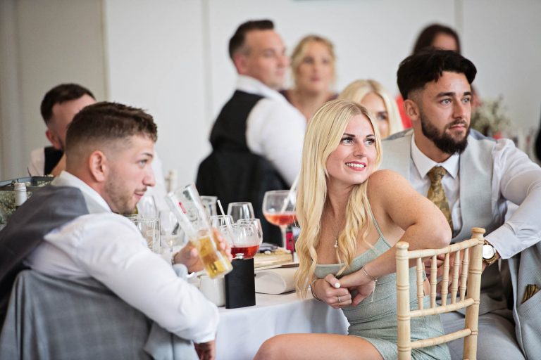 Candid photo taken of wedding guests at Margam Country Park, during the wedding speeches by Blooming Photography.