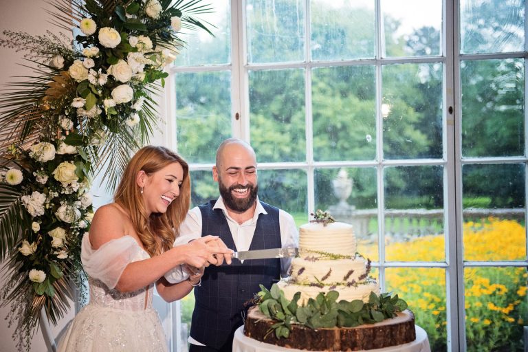Candid photo of bride and groom cutting their wedding cake at Margam Country Park, taken by Blooming Photography.
