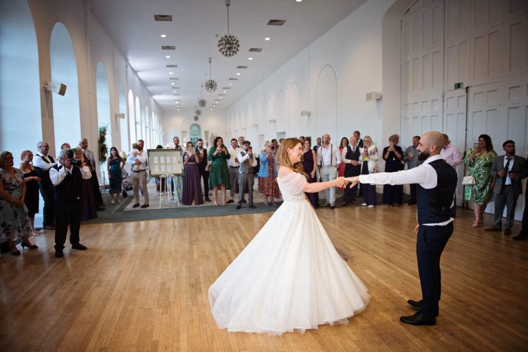 Candid colour photo of bride and groom doing their first dance at Margam Country Park, taken by Blooming Photography.