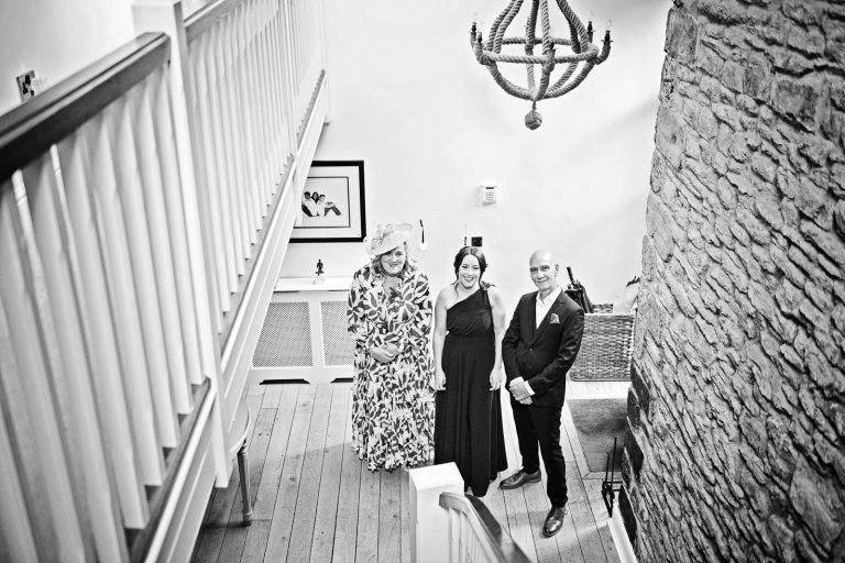 Storytelling photo of parents and sister waiting for the bride to walk down the stairs. Cardiff wedding photographer, Blooming Photography