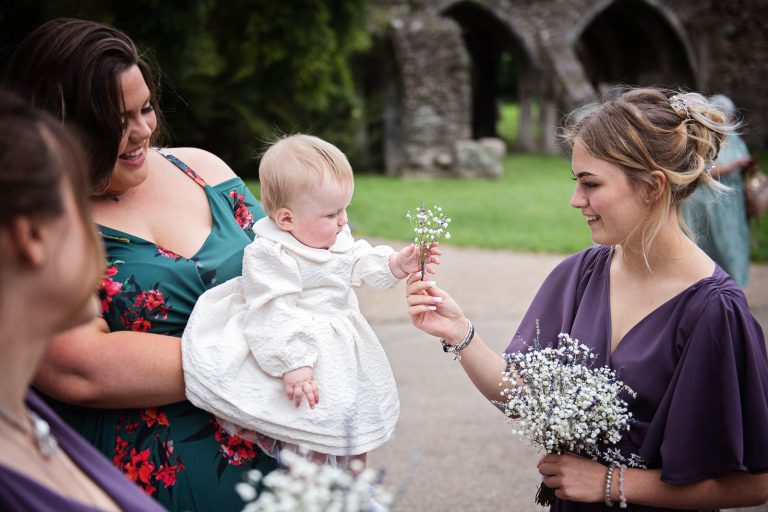 Natural wedding photo of flower girl and bridesmaid playing with the wedding flowers. Photographed by Blooming Photography at Margam Country Park.