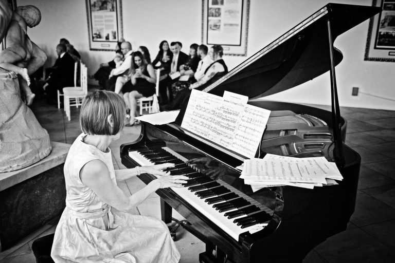 Black & White image of a pianist playing on a grand piano at Margam Country Park. Photographed by Blooming Photography