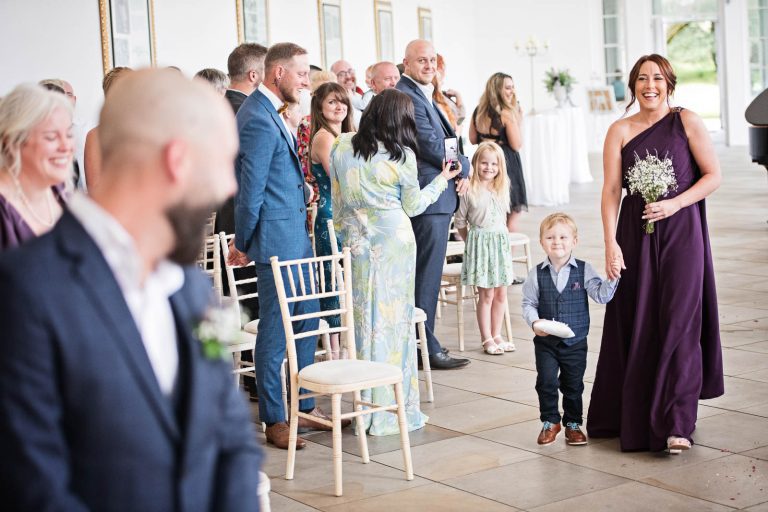 Ring bearer and bridesmaid walking down the wedding isle at Margam Country Park. Photographed by Blooming Photography