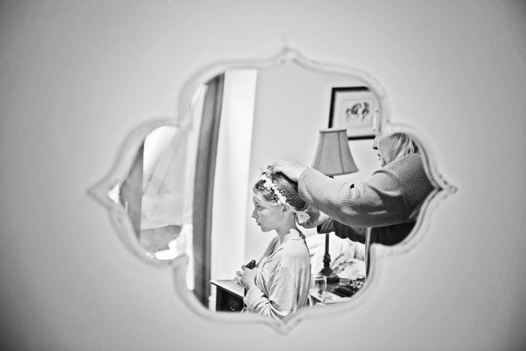 B&W candid photo of bridesmaid reflective in mirror by Cardiff wedding photographer, Blooming Photography