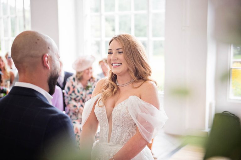 Candid photo of a bride and groom exchanging their vows at a wedding at Margam Country Park. Photographed by Blooming Photography
