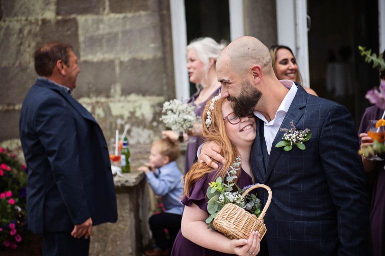 Candid photo of groom hugging a relative taken at a wedding at Margam Country Park by Blooming Photography.