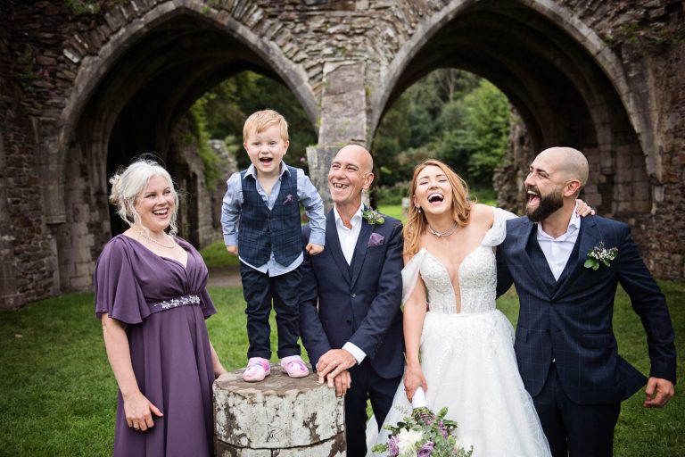 Fun family wedding group photo with everyone laughing. Photo taken at Margam Country Park by Blooming Photography.