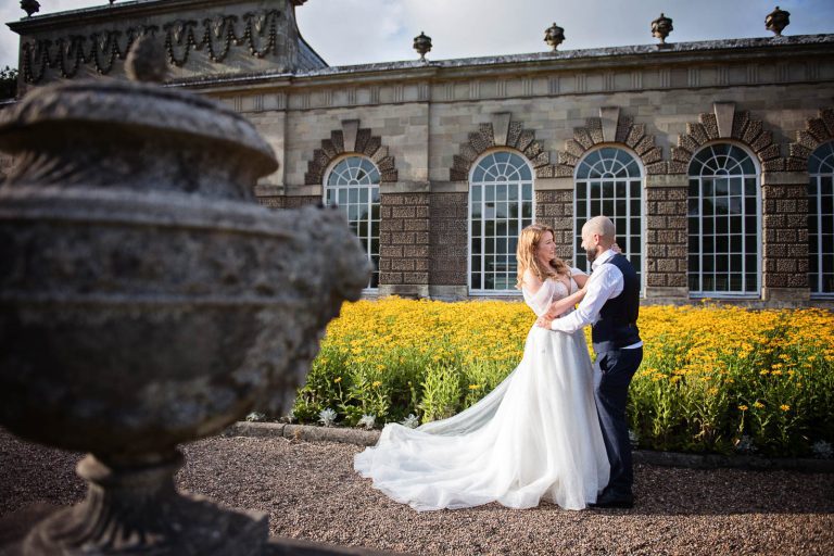Natural wedding photograph of bride and groom hugging and smiling at Margam Country Park photo by Blooming Photography.