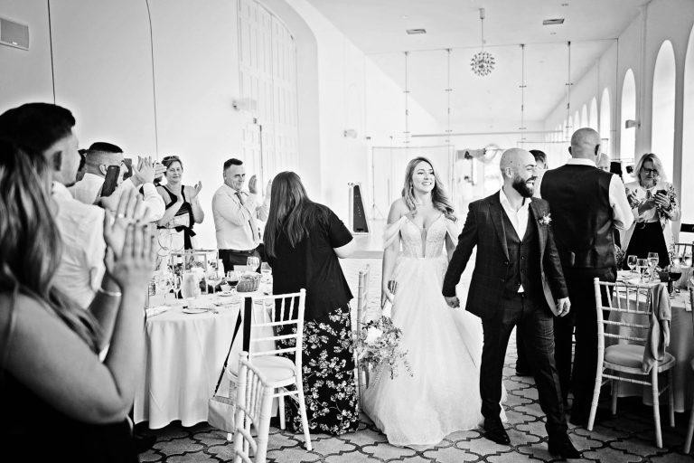 Candid image taken of the bride groom entering the wedding breakfast room cheered on by friends and family at Margam Country Park, by Blooming Photography.