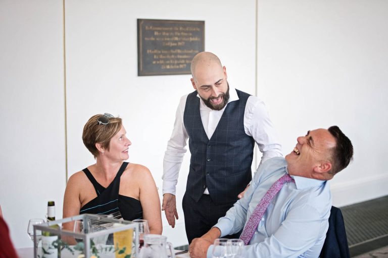 Candid image taken of the groom chatting and laughing with his friends at Margam Country Park, during the wedding breakfast by Blooming Photography.