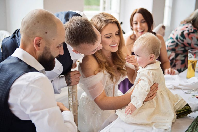 Candid image taken at Margam Country Park, of bride with a baby by South West Wedding Photographer, Blooming Photography.