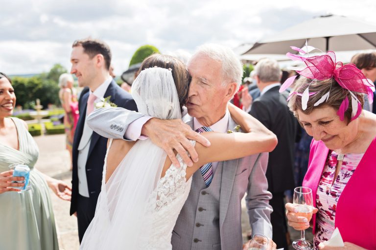 The father of the groom hugs the bride. Colourful photograph. Photographed at Danesfield House Hotel and Spa. Photography by Ben Roberts Blooming Photography.