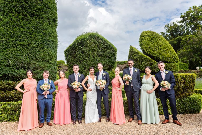 Fun group shot of the bridal party. Groomsmen hold the bridesmaids flowers. Fun and relaxed. Photographed at Danesfield House Hotel and Spa. Photography by Ben Roberts Blooming Photography.
