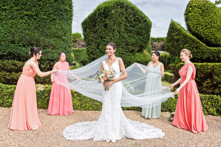 Bridesmaids layout the brides wedding veil. Elegant shot with the formal gardens at Danesfield House behind them. Photography by Ben Roberts Blooming Photography.
