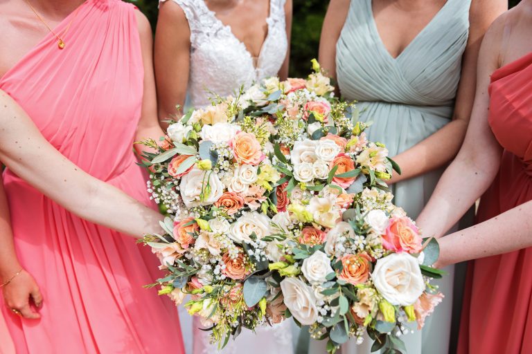 Bride and bridesmaids hold out their wedding bouquets into one big bunch. Photographed at Danesfield House Hotel and Spa. Photography by Ben Roberts Blooming Photography.