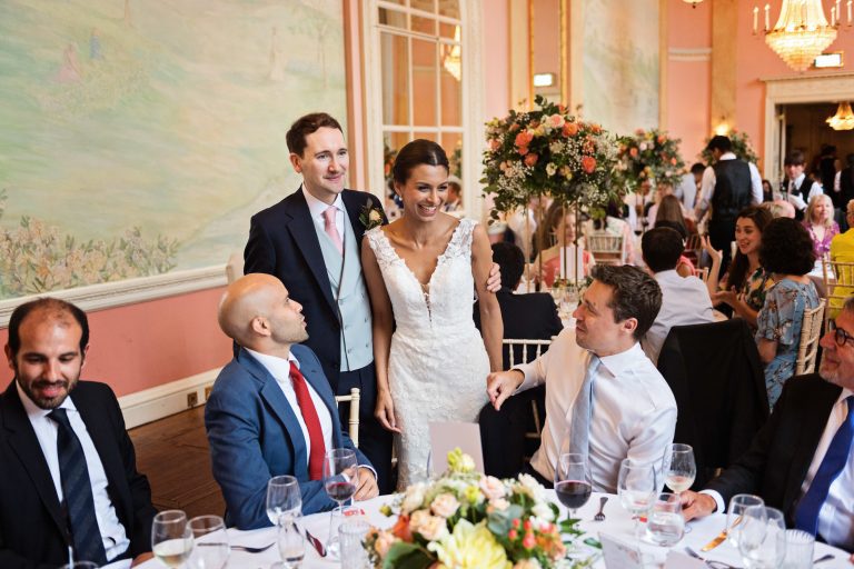 Bride and groom chat with guests during the wedding breakfast in the ballroom at Danesfield House