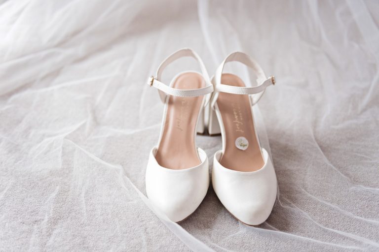 Wedding shoes on top of veil. Photography by Blooming Photography.