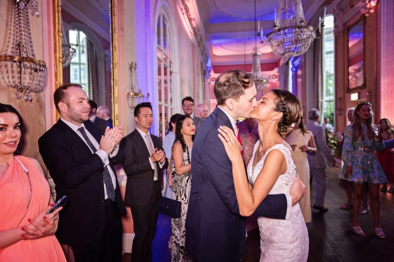 Bride and groom kiss to the applause of their guests. Photographed in the elegant Danesfield House Hotel and Spa Ballroom. Photograph by Ben Roberts, Blooming Photography.