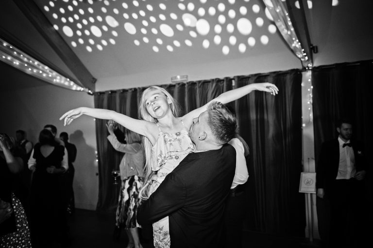 B&W image of a child being held by the dad during a dance. Candid photo by Blooming Photography. Taken at Blackwell Grange, Warwickshire.