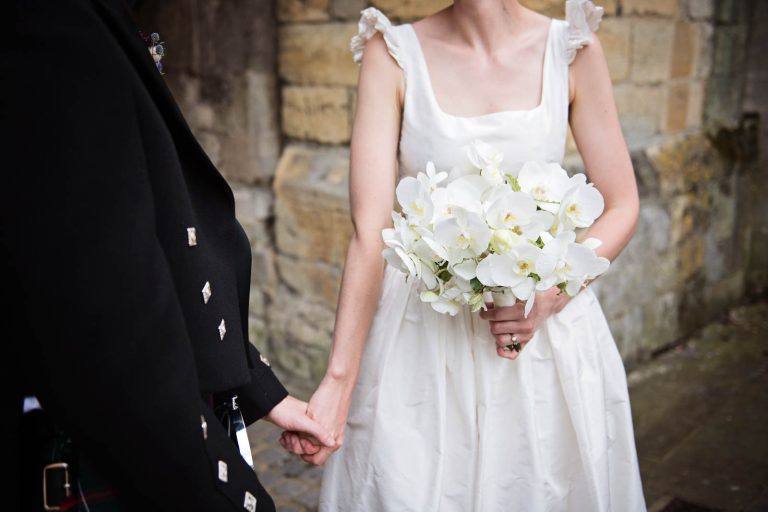 Candid wedding photo of bride and groom holding hands in Winchester, photo by Blooming Photography.