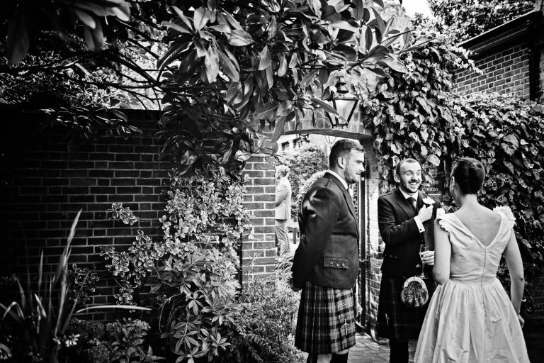 Candid wedding photo of guests talking to bride at Hotel Du Vin Winchester, Black & white photo by Blooming Photography