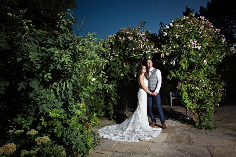 Evening photo of bride and groom in the rose garden at Kingscote Barn