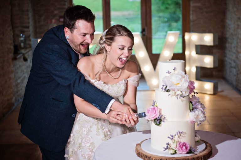 Bride and groom cut wedding cake Kingscote Barn
