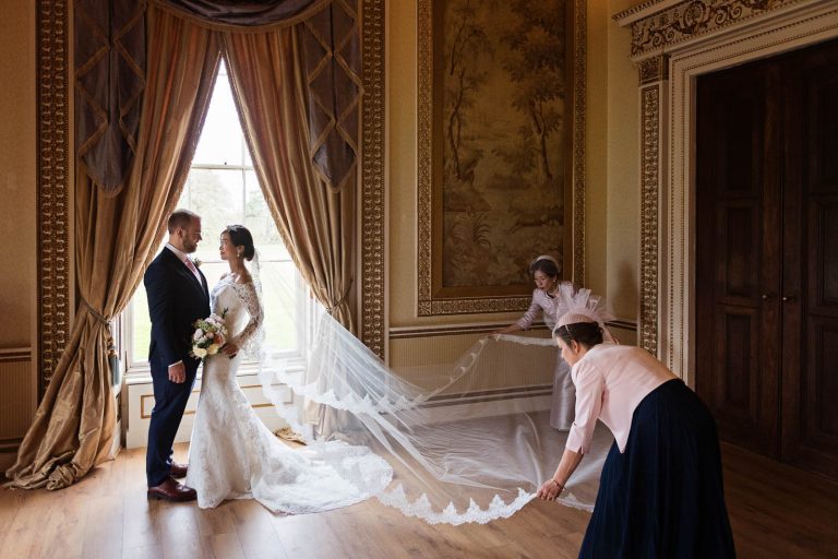 Mother of the bride and mother of the groom lay out the brides wedding veil in the tapestry room in Leigh Court. Candid photograph by Blooming Photography.