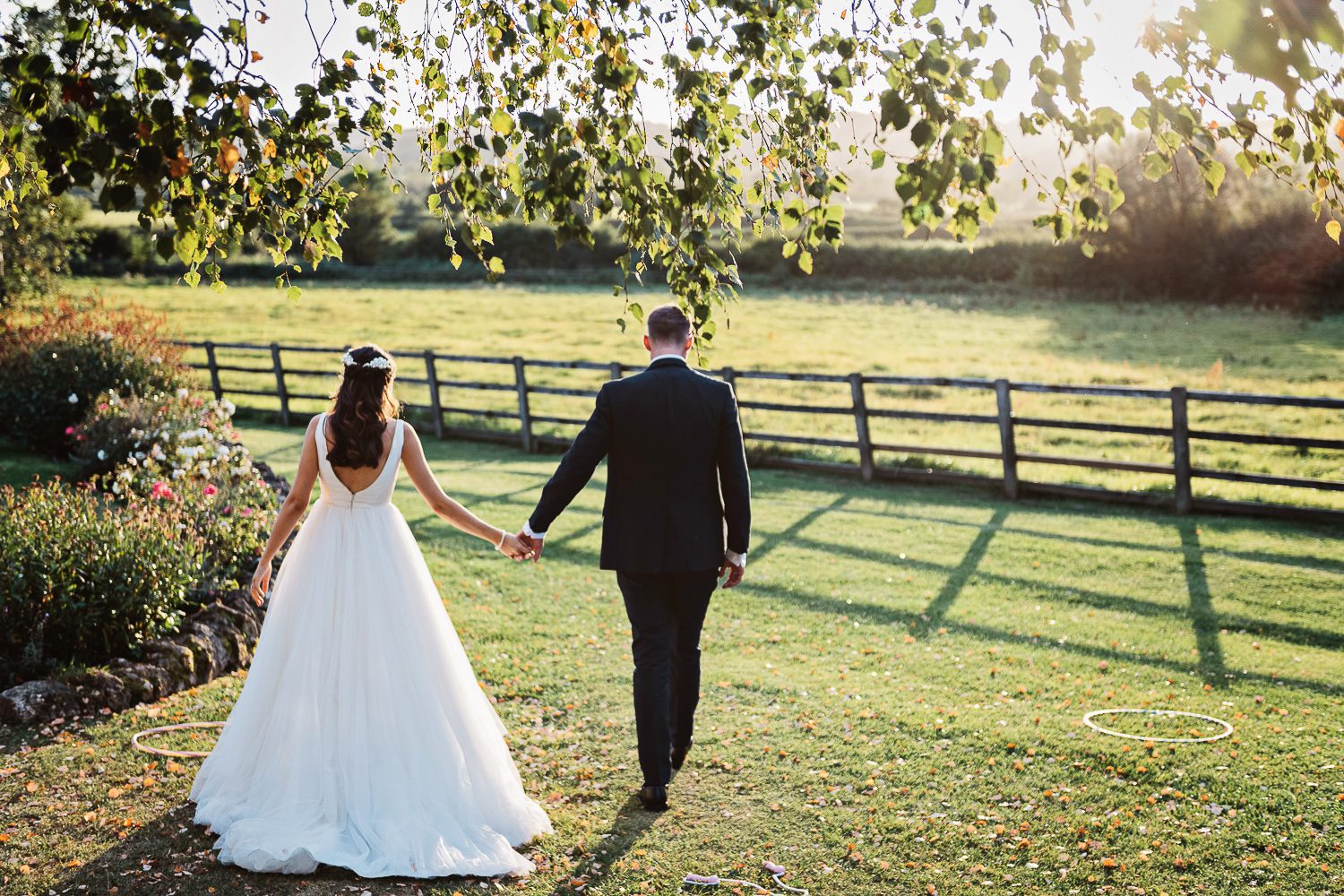 Bride and groom walk away from camera holding hands in Storytelling way.