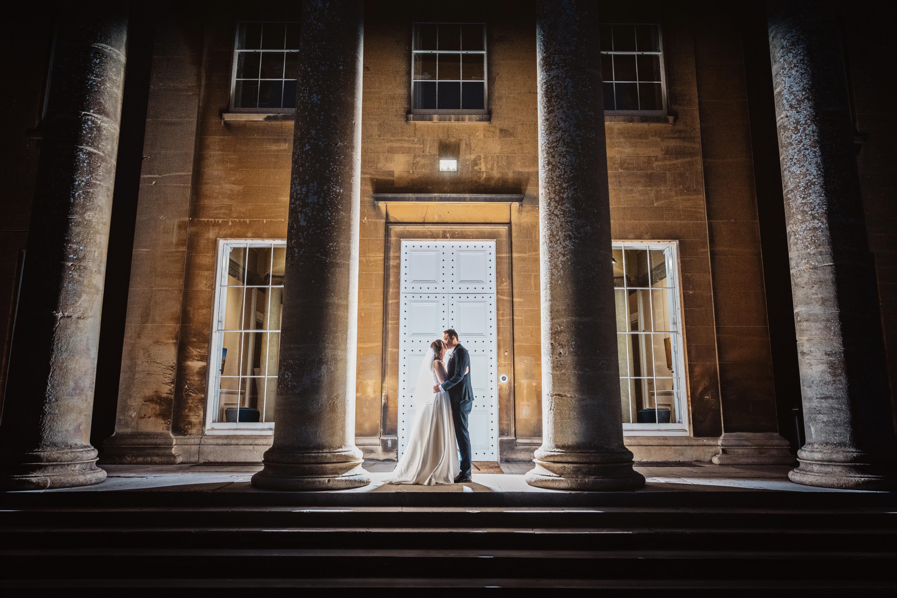 Exterior night time shot of bride and groom lit up by off camera flash at the top of the stairs outside at Leigh Court.